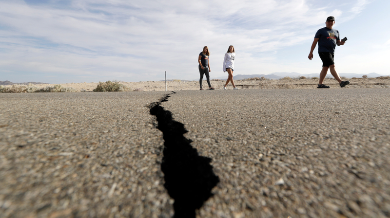 People crossing Highway 178 next to a crack left created by the Ridgecrest earthquake in July.